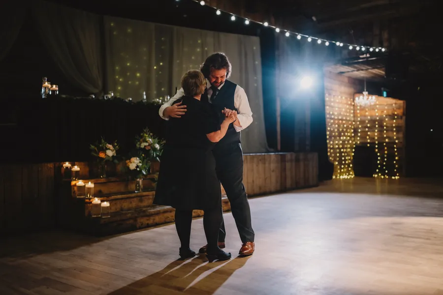 Le marié danse avec sa mère sous des guirlandes lumineuses