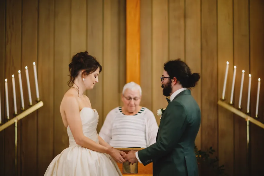Vue plus large du couple et de l'officiante entre des candélabres en laiton