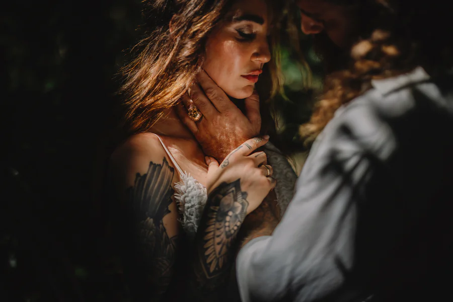 La mariée dans les bras de son conjoint, le visage éclairé par une lumière chaude et basse