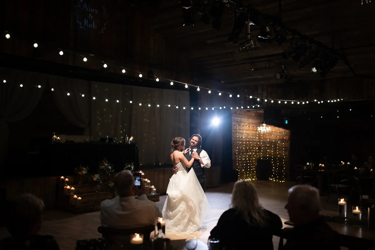 Première danse du couple sous des guirlandes lumineuses, dans une salle sombre (Originale)