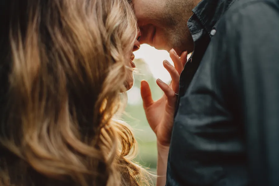 Gros plan d'un couple sur le point de s'embrasser, le soleil dans ses cheveux