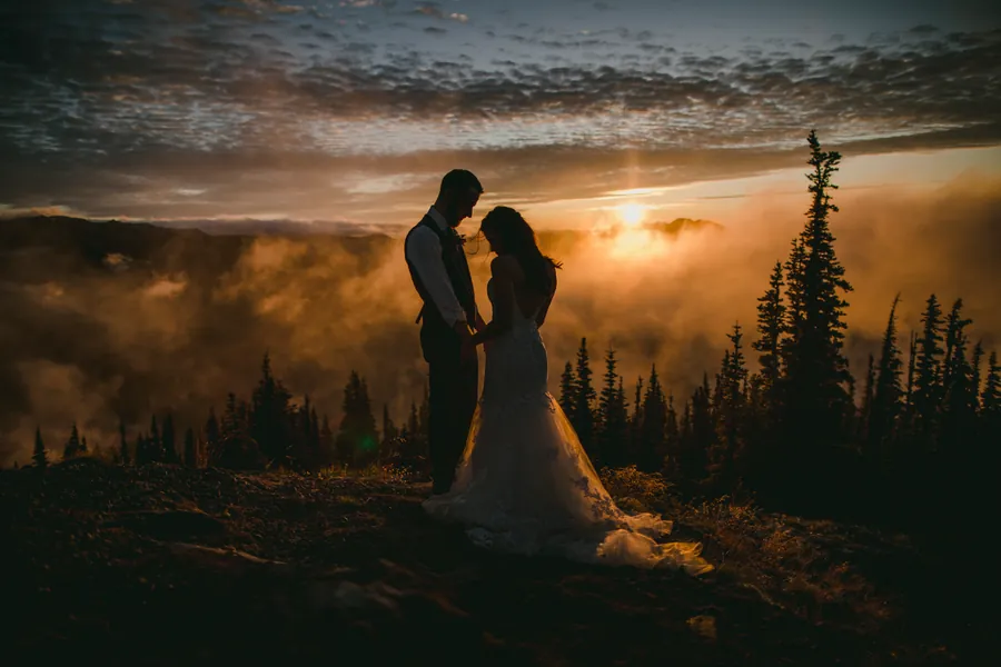 Couple au lever du soleil, au-dessus d'une mer de brouillard et de conifères
