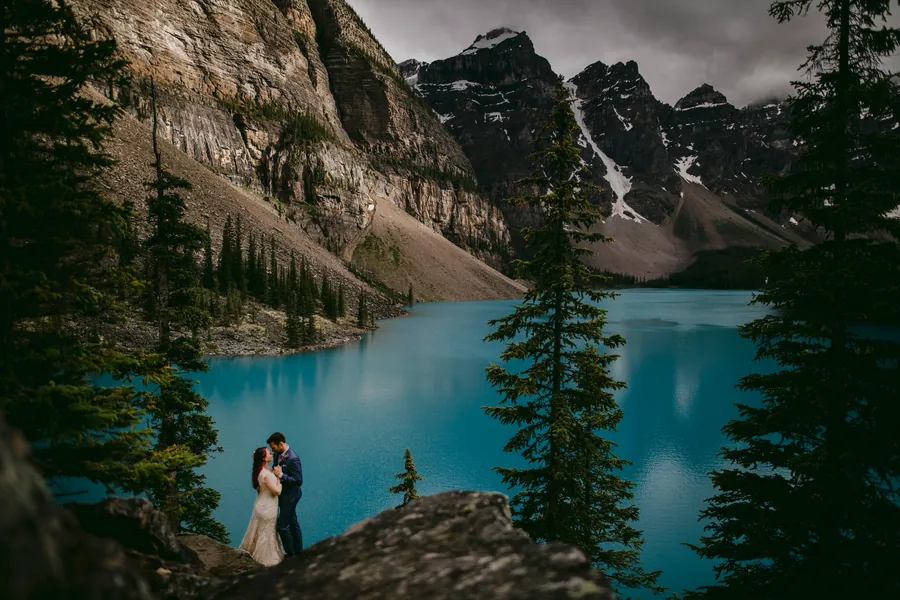 Couple sur une corniche rocheuse, au-dessus d'un lac de montagne turquoise