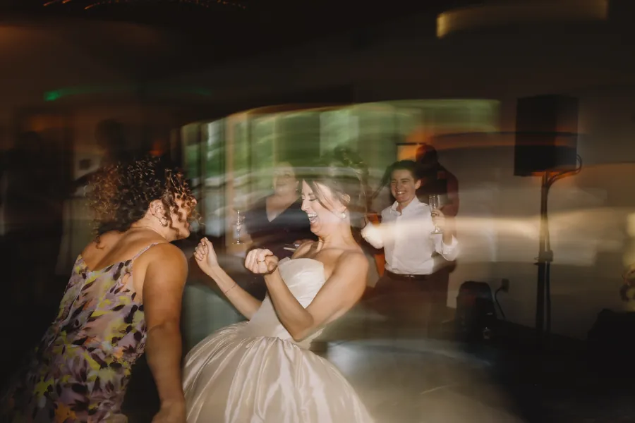 La mariée rit et danse avec une amie pendant la réception