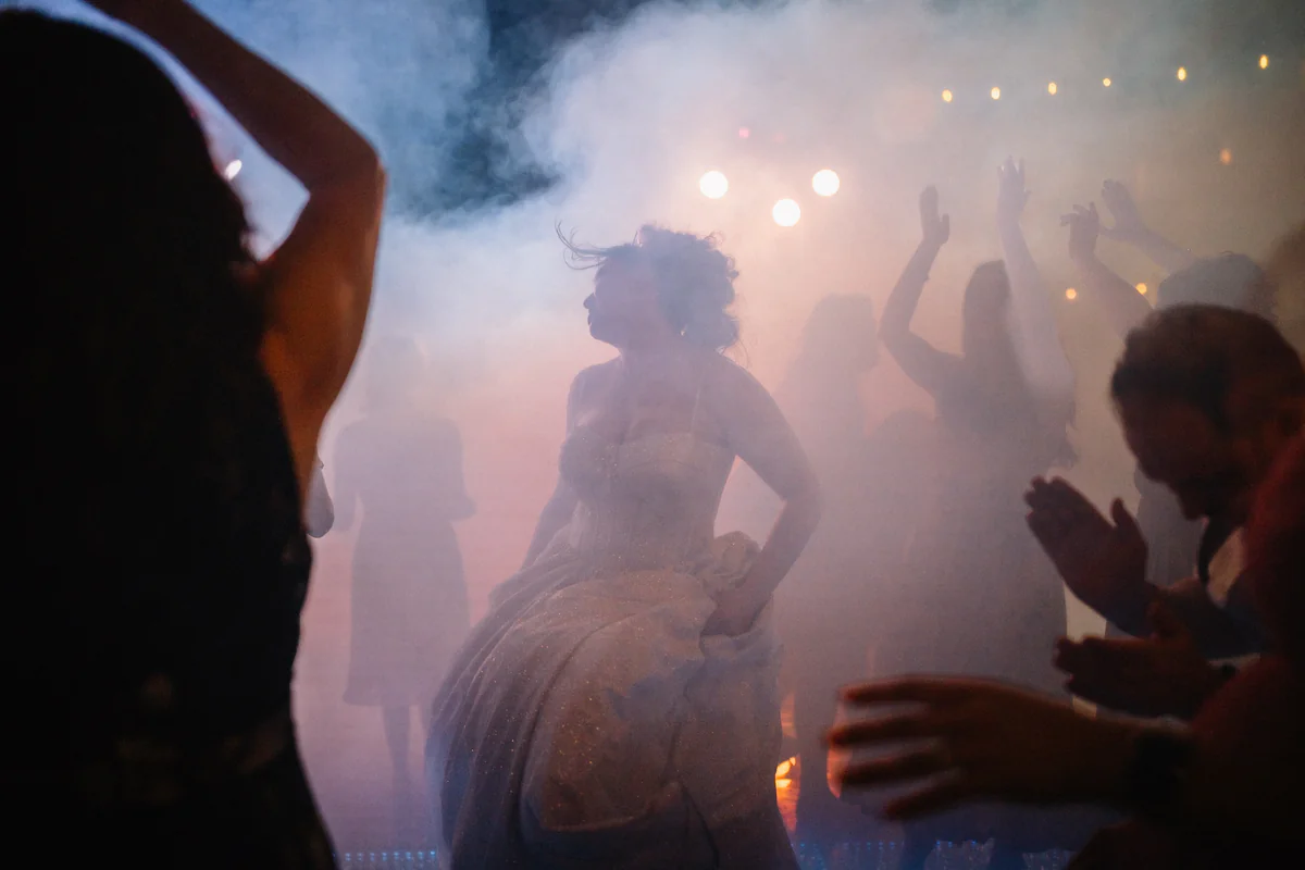 La mariée danse dans la fumée tourbillonnante et les lumières colorées sous les acclamations des invités (Retouche PHAiTO)