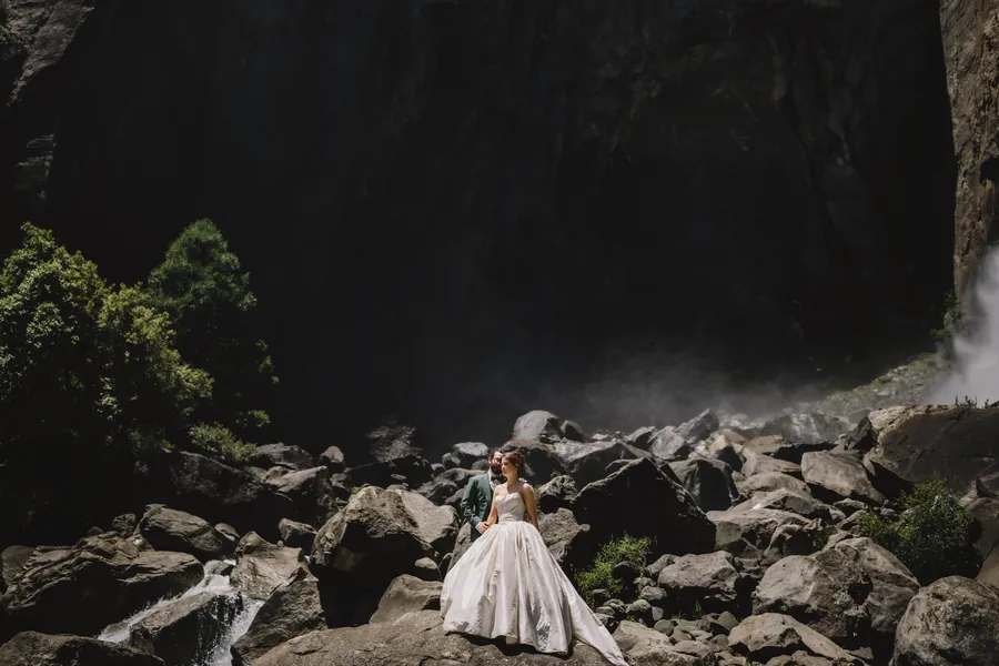Couple sur un champ de rochers, dans l'ombre profonde, près d'une chute lumineuse