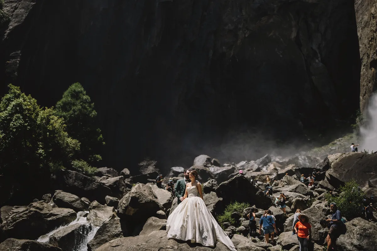 Couple sur un champ de rochers, dans l'ombre profonde, près d'une chute lumineuse (Retouche PHAiTO)