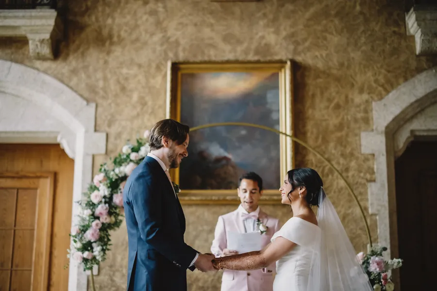 Le couple échange ses vœux près d'une fenêtre lumineuse, sous un grand tableau